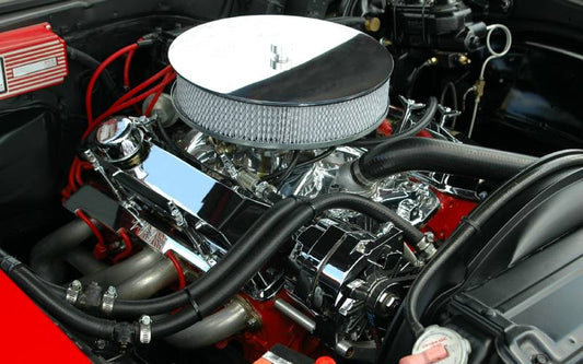 Internal look at a race car engine. Many of the parts are clean and shiny, with a visible red chassis surrounding it.