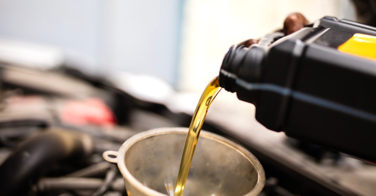 A mechanic is pouring engine oil into a motor through a funnel. The engine performs better when it has new oil.