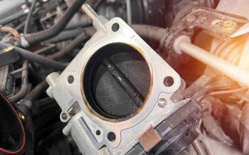 A close-up of a throttle valve of a vehicle's engine. Visible signs of carbon buildup are on the valve.