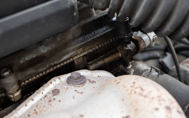 Close-up view of the interior of a car's engine. There is a distinct buildup of oil around the vehicle's head gasket.