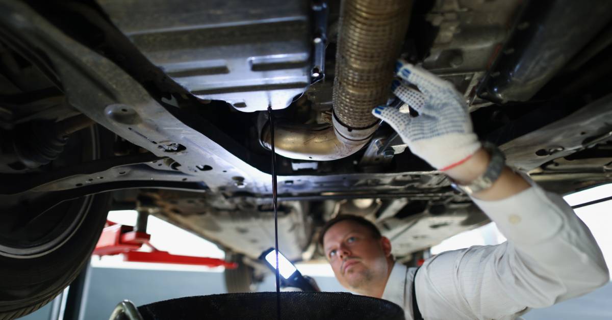 A race car pit crew member works to change the oil so that it is ready to continue winning races with its driver.