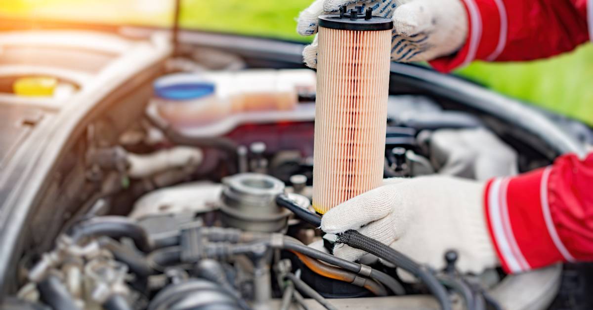 A mechanic holds up a replacement oil filter to use to change out the old oil filter on a race car driver’s vehicle.